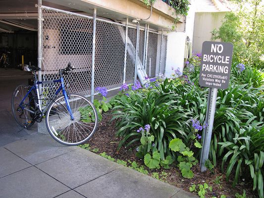 Bike locked to fence with no bike parking sign